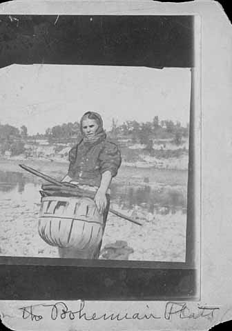 Photo of woman near the Mississippi river, carrying a basket of wood, ca. 1900.