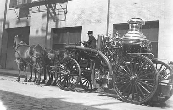 Photo of a fireman posed with a horse-drawn fire engine, 1905.