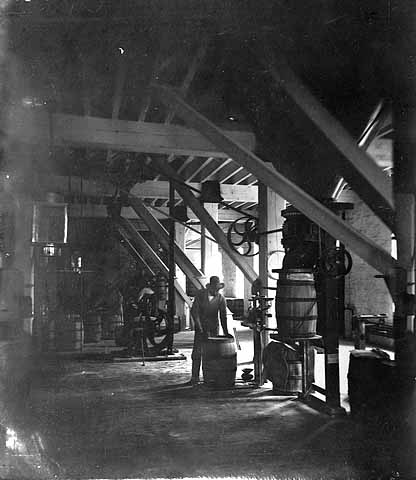 Photo of worker loading flour into a barrel on the packing floor at the Washburn A Mill, ca. 1875.