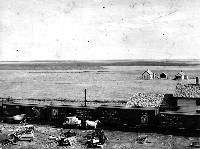 Photo of farm implements after being removed from a train in the prairie, 1895.