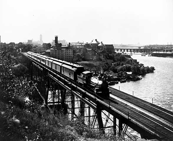 Photo of a train crossing the Mississippi River on a bridge near the University of Minnesota, 1900.