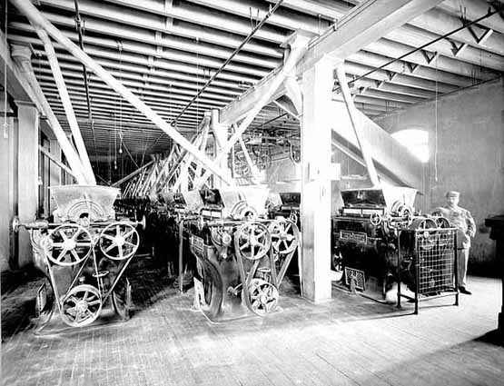 Photo of Pillsbury-Washburn mill interior showing three rows of roller mill stands and one worker, 1897.