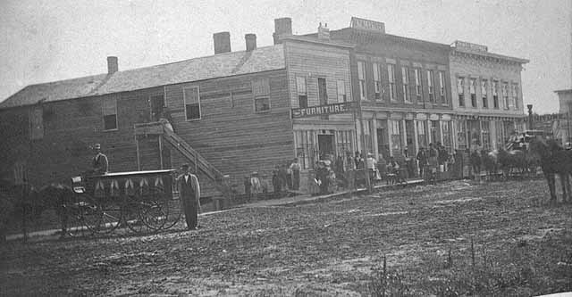 Posed photograph of a main street in Rochester with dirt road, 1870.