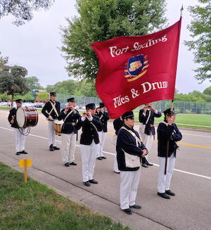 Fife and drum corps marching with flag.