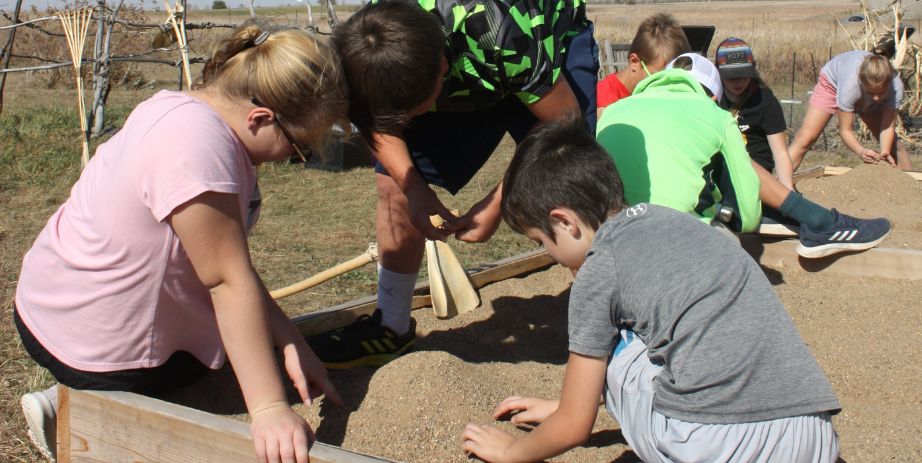 Children work in a garden setting with historic reproduction tools